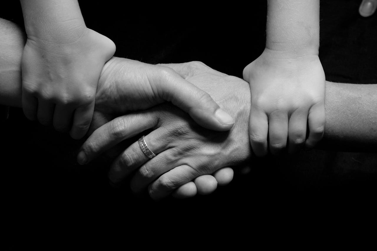 Home Monochrome image of a child's and adult's hands clasped together symbolizing trust and connection.