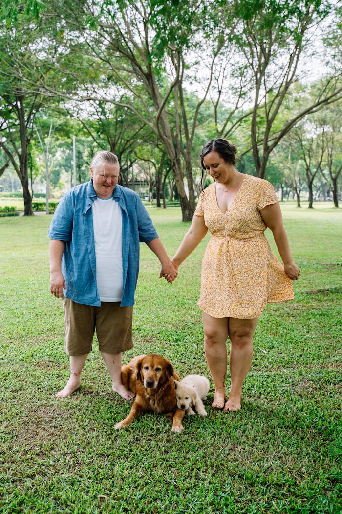 Home A couple enjoying a day in the park with their golden retrievers, showcasing love and companionship.