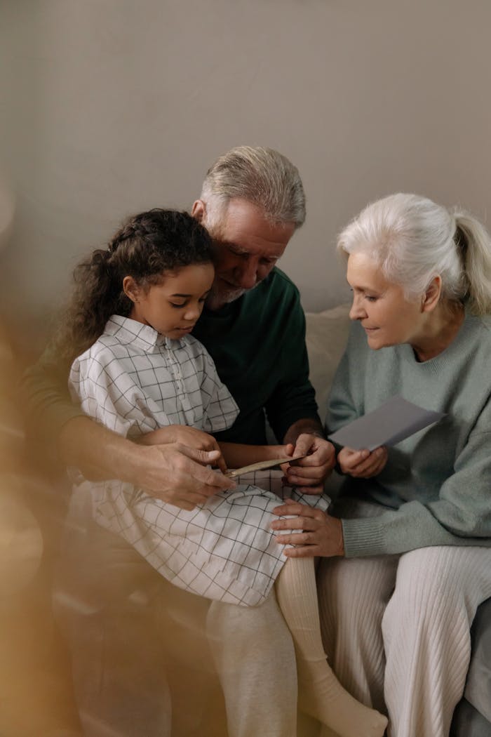 Home Grandparents sharing a heartfelt moment reading with their granddaughter indoors.